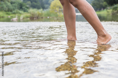 Woman legs while standing the river. Focus on right leg © SKT Studio