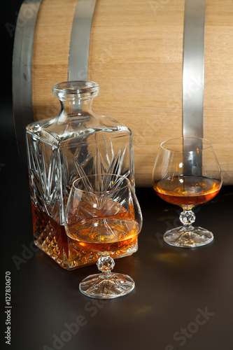 Glass of brandy and a carafe on background oak barrels