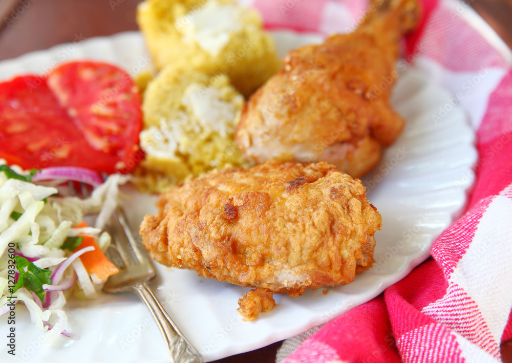 Chicken thigh and leg fried Southern-style with cornbread and vegetables Chicken thigh and leg fried Southern-style with cornbread and vegetables