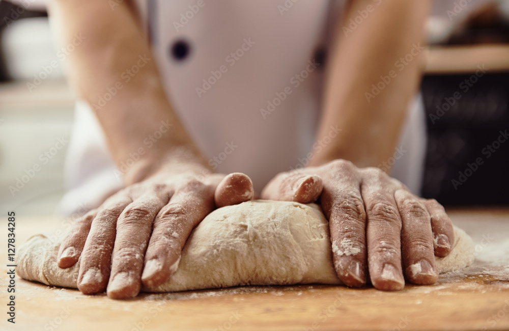 Woman chef kneading pizza dough in the kitchen. 