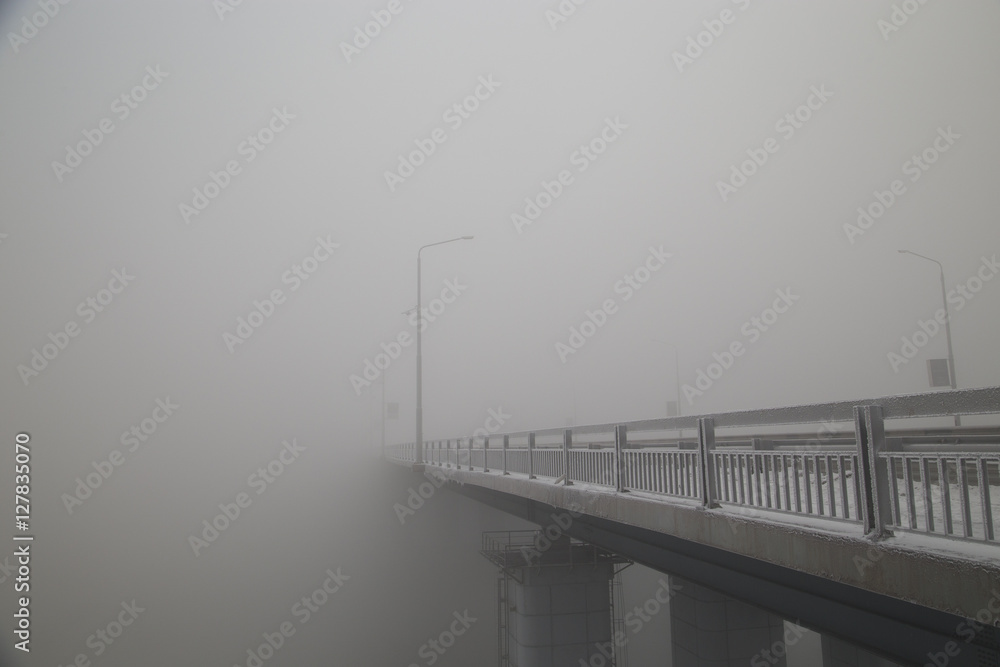 The bridge over the river lost in the thick fog.