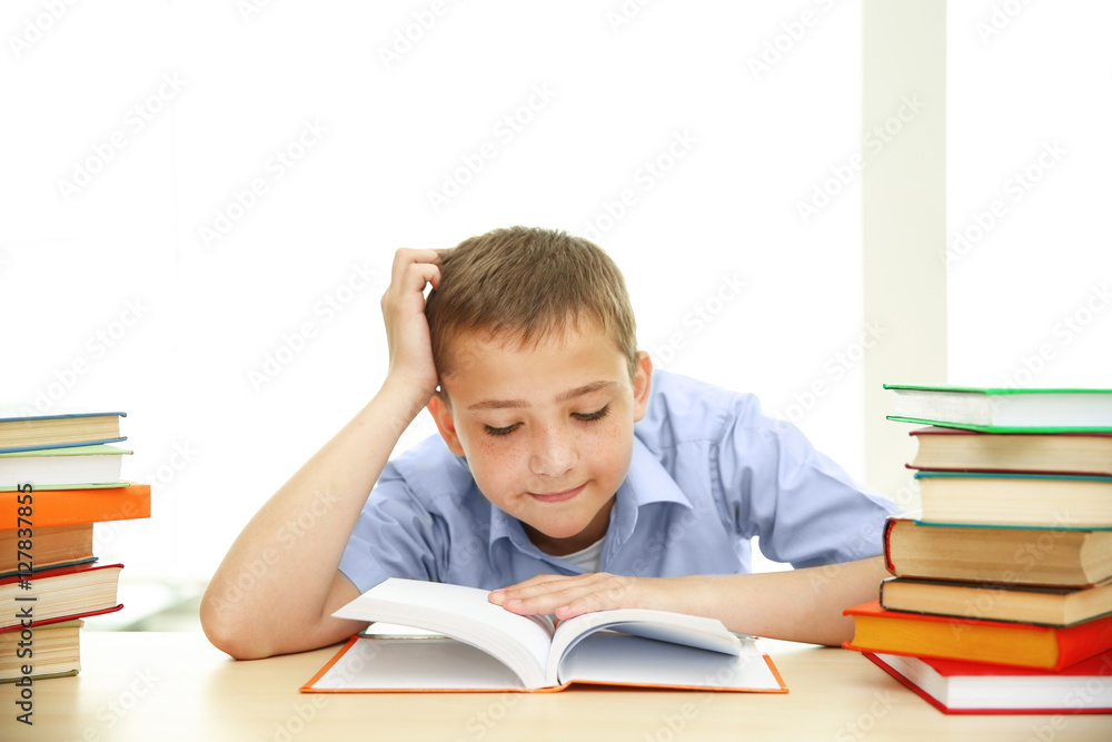 Smiling boy with many books at school