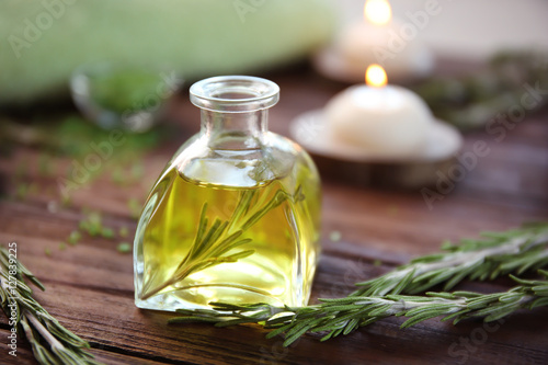 Bottle of rosemary essential oil on wooden table