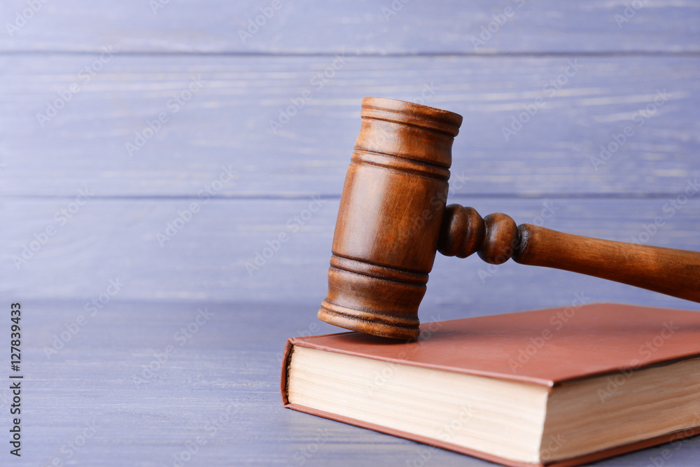 Judge's gavel and book on wooden wall background