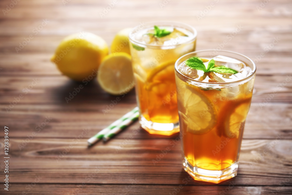 Glasses of iced tea with lemon slices and mint on wooden background Glasses of iced tea with lemon slices and mint on wooden background