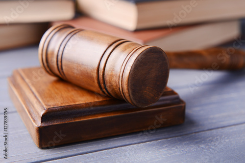 Gavel with sound block and books on wooden background, closeup