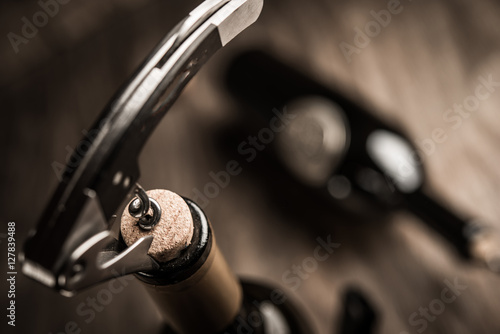 Bottle of wine and corkscrew over wooden background