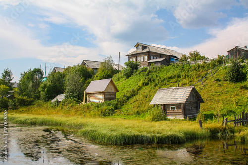 North Russian village Isady. Summer day, Emca river, old cottages on the beach. photo