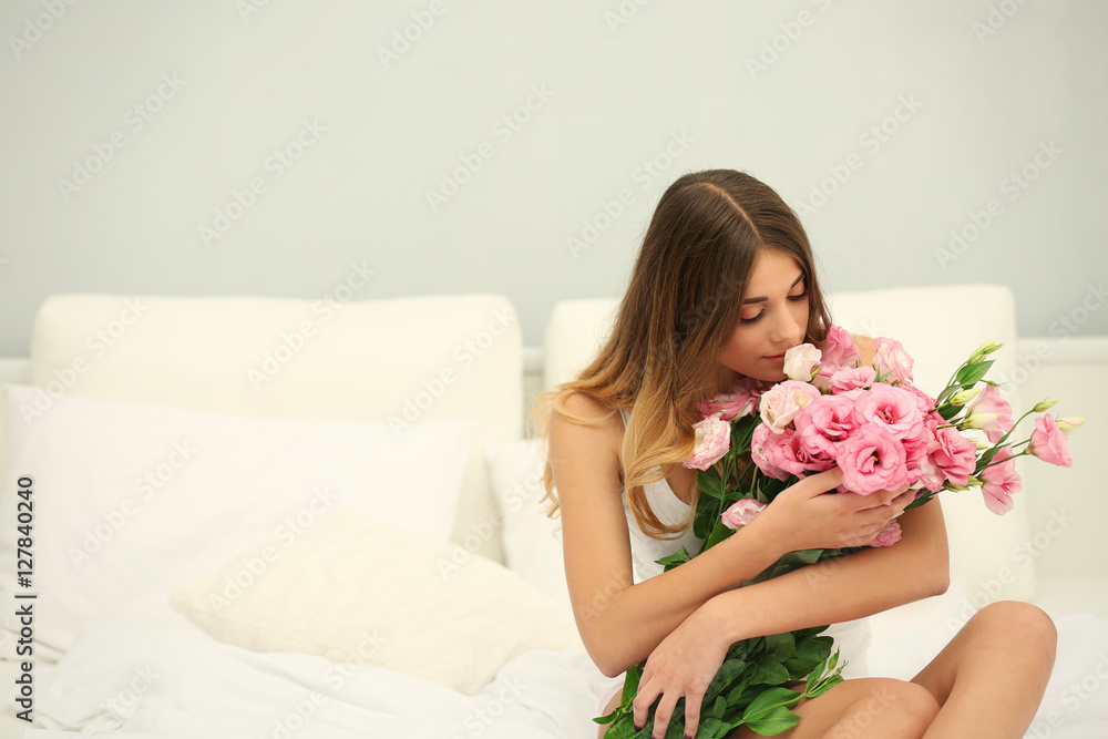 Pretty girl in bed with big bouquet of flowers