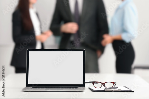 Working place with computer and business people on background