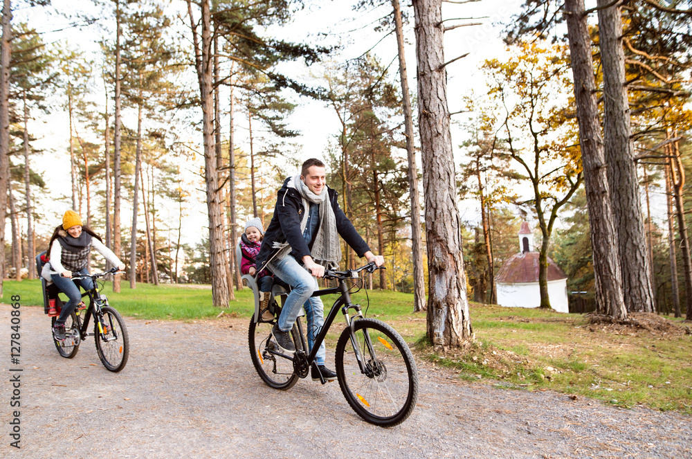 Young family in warm clothes cycling in autumn park