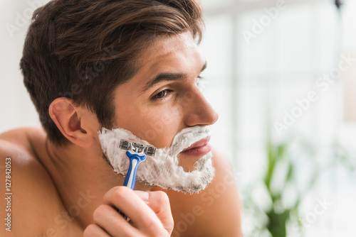 Serious guy shaving his beard photo