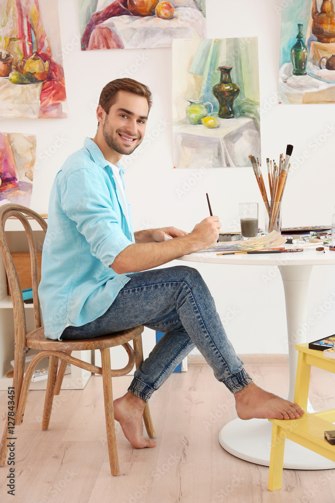 Young male artist painting picture in studio Young male artist painting picture in studio