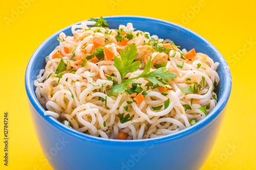 Bowl of instant noodles on yellow background.
