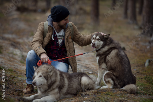 Photography young handsome attractive bearded model man with his two dogs in forest