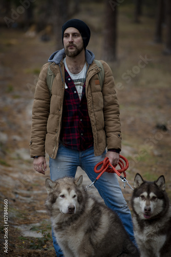 Canvas Print young handsome attractive bearded model man with his two dogs in forest
