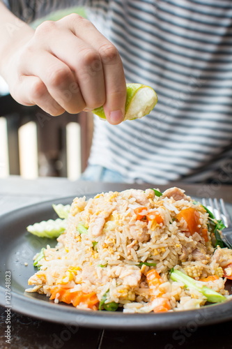 Female hand squeezing lime on fried rice