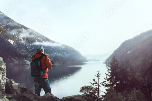 Hiker stands at sunrise on mountain lake