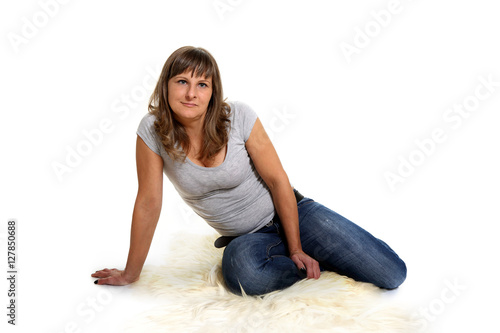 Kobieta siedzi na skórze naturalnej, na białym tle.