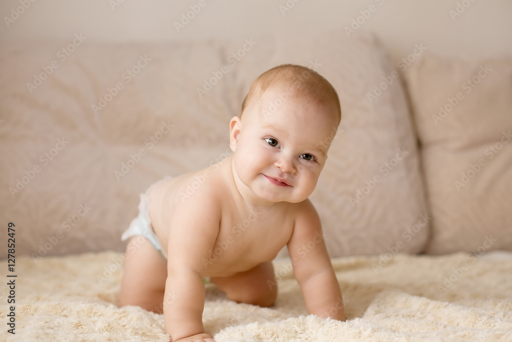 Cute smiling baby in diapers on a beige couch. Cute smiling baby in diapers on a beige couch.