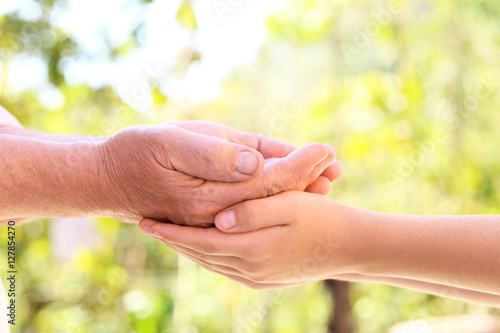 Hands of young child and old senior