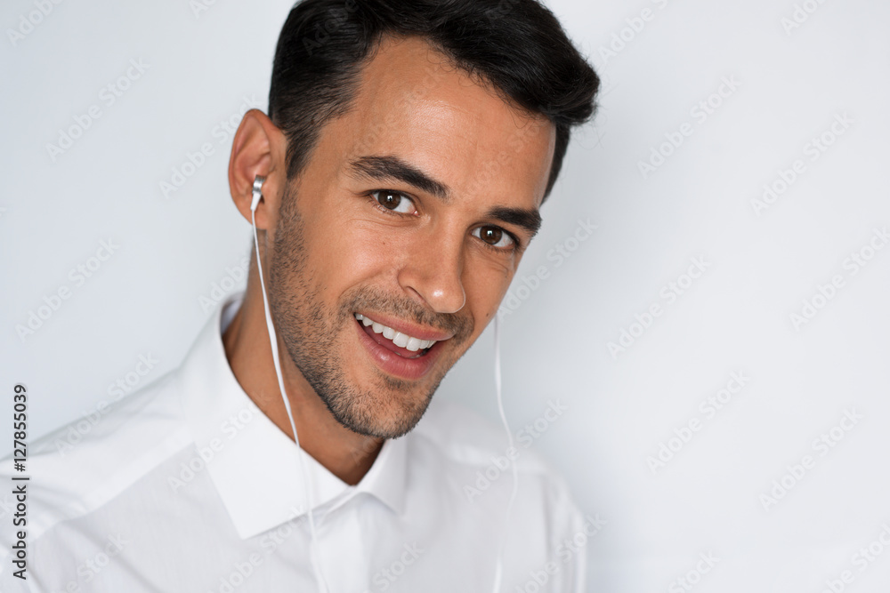 Portrait of handsome caucasian young man enjoying his favorite music. Happy stylish smiling man in headphones against gray background. Singing a song. Portrait of handsome caucasian young man enjoying his favorite music. Happy stylish smiling man in headphones against gray background. Singing a song.