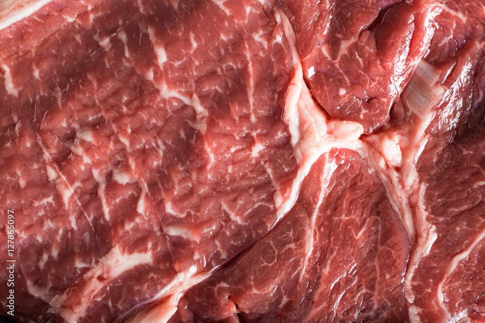 Fresh steak served with spices, tomatoes and leafs of basil on marble background. Uncooked beefsteak cooking on a kitchen. Delicious, spicy, juicy meat with copy space closeup. Fresh steak served with spices, tomatoes and leafs of basil on marble background. Uncooked beefsteak cooking on a kitchen. Delicious, spicy, juicy meat with copy space closeup.