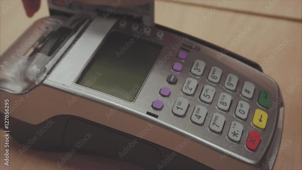 Woman's hand pushing the button and swipe credit card payment on pos terminal standing on wooden desk Woman's hand pushing the button and swipe credit card payment on pos terminal standing on wooden desk