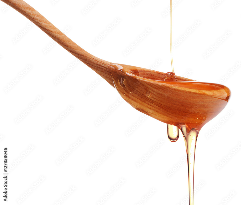 Honey dripping from a wooden honey dipper isolated on white back Honey dripping from a wooden honey dipper isolated on white back