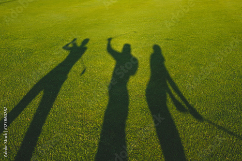 Foto Three golfers with open hands silhouette on grass