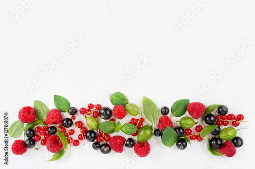 Various fresh summer berries. Ripe raspberries  currants  gooseberries  mint and basil leaves. Berries on white background. Top view