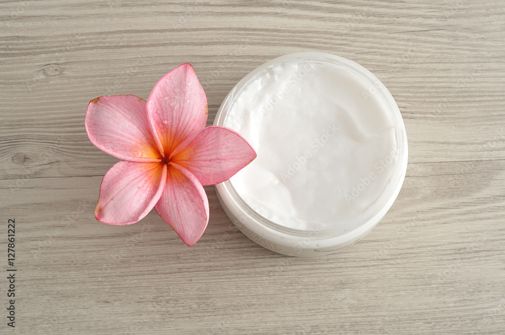 Body lotion in a container with a pink frangipani flower Body lotion in a container with a pink frangipani flower
