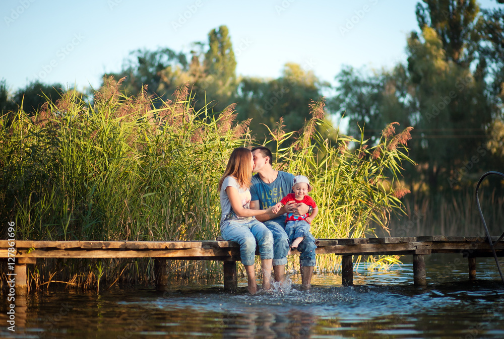 Family, mother, father and child playing and spending time with his young son in the summer the river or lake Family, mother, father and child playing and spending time with his young son in the summer the river or lake