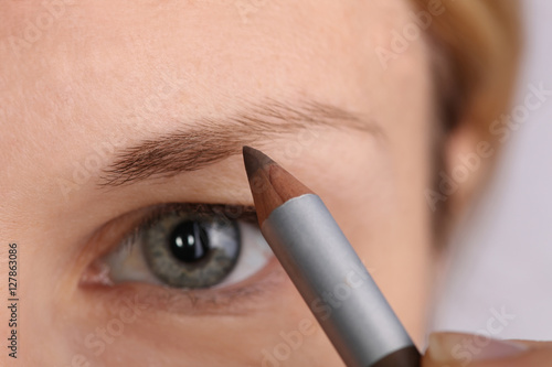 Young beautiful woman applying eyebrow pencil close up. Beauty, make up concept photo