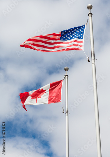 American and Canadian flag on poles hanging on a flag pole in th