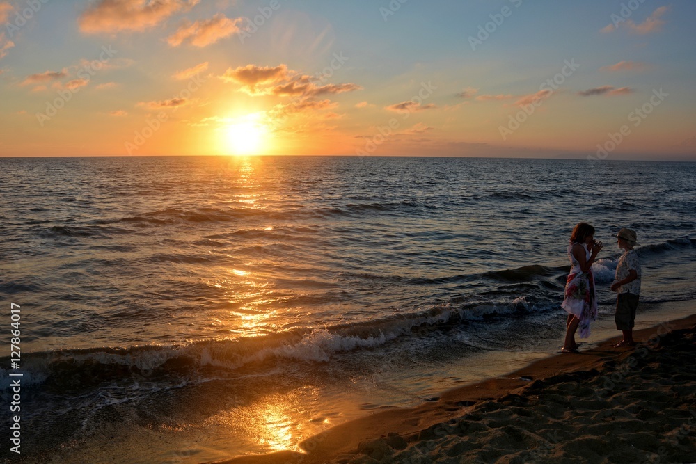 Mädchen und Junge stehen rechts beim Sonnenuntergang am Strand