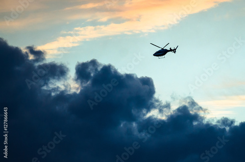 Silhouetted Helicopter Flying Across a Sunset Sky