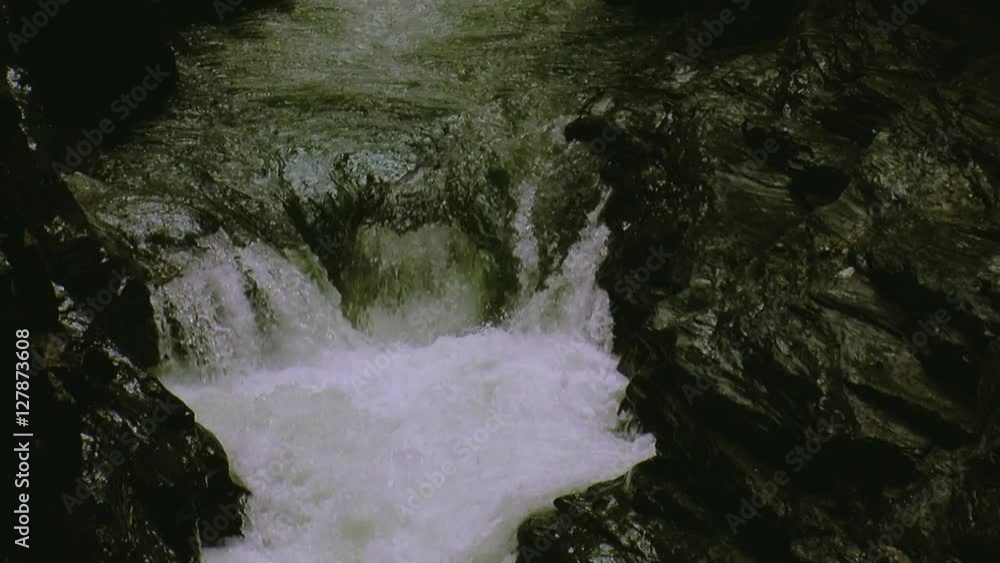 Water of stream flows from rocks into hole. Splash. Summer day. Landscape. Nature. Wet stones. Spray. Warm shades. Water of stream flows from rocks into hole. Splash. Summer day. Landscape. Nature. Wet stones. Spray. Warm shades.