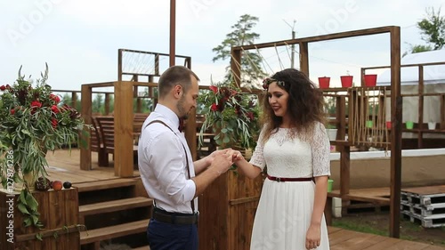 Charming, the groom wears wedding ring on the finger of his bride. Concept: wedding rustic.