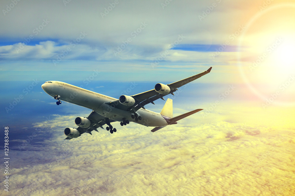 Obraz premium air plane flying over cloud scape and sun light behind