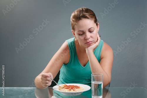 Portrait of woman with no appetite in front of the meal. Concept of loss of appetite