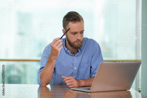 Thoughtful Middle-aged Man Working on Laptop