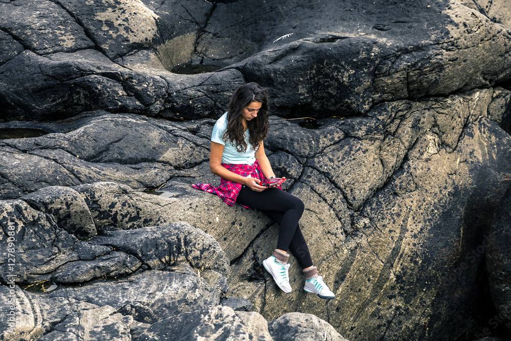 Young woman is sitting among the curve stones in Norway Young woman is sitting among the curve stones in Norway