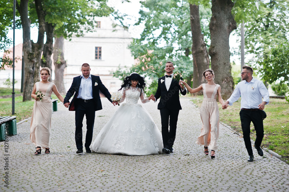 Fine wedding couple with bridesmaids at beige dress and groomsma
