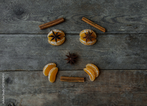 face with mandarin, anise and cinnamon on wooden background