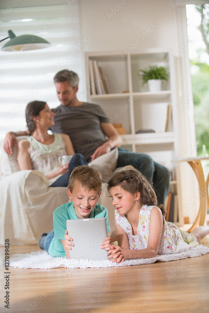 Cheerful family at home. two kids playing with a digital tablet Cheerful family at home. two kids playing with a digital tablet