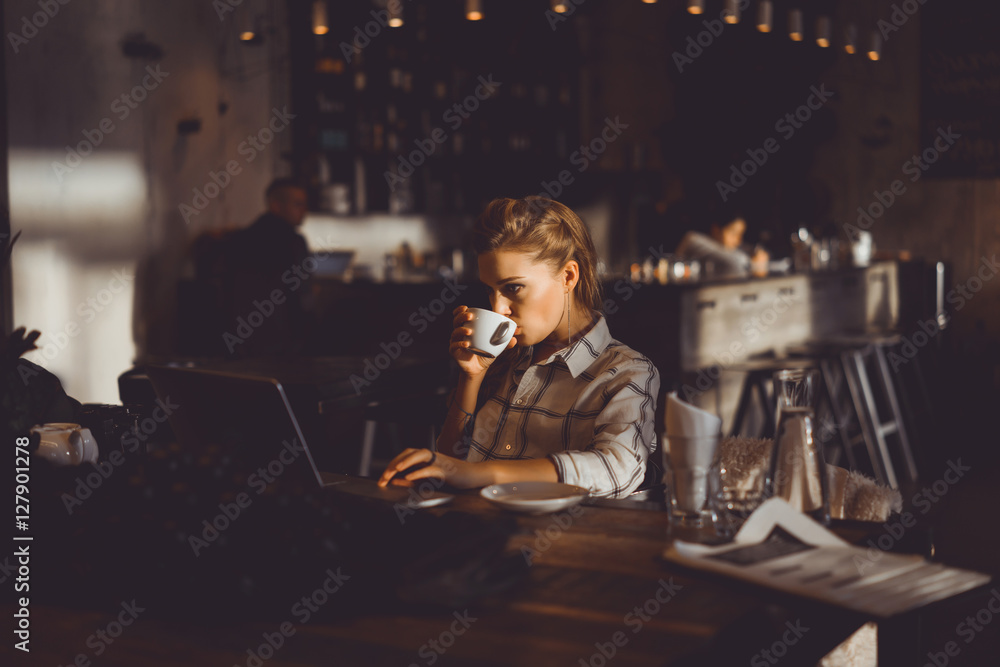 outdoor portrait of a young girl she works as a freelancer in a cafe drinking a delicious hot Cup of coffee from text send mail loads the photo instagram freelancer drinking cappuccino in sunglasses
