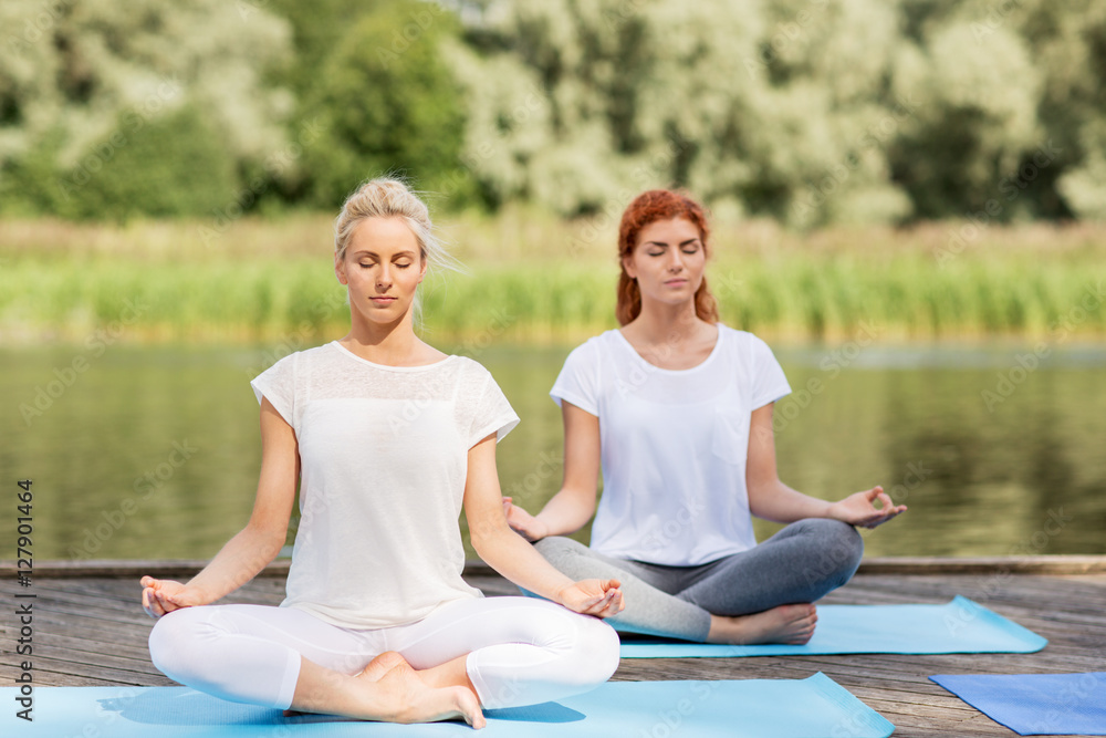 women meditating in yoga lotus pose outdoors