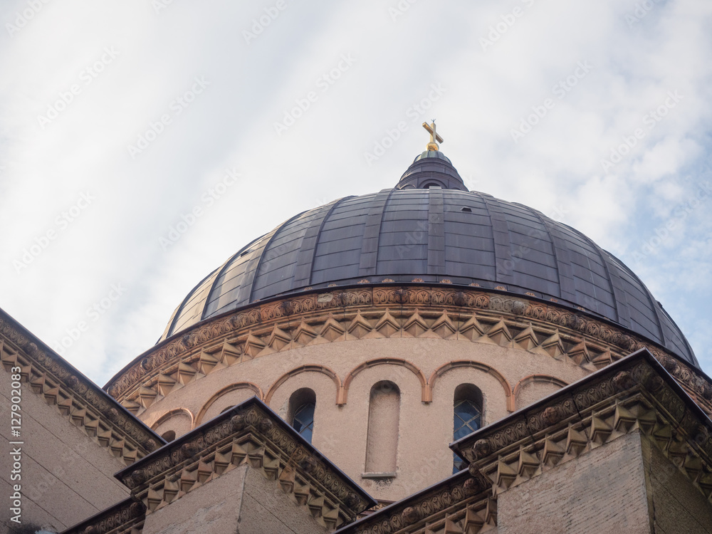 Picture of the dome of the cathedral from below. Building with dark dome and sculpting on the light-beige coloured wall. Holy Cross on the dome of the cathedral.