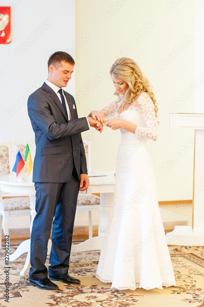 Невеста надевает обручальное кольцо на палец жениха. Свадьба, роспись в ЗАГСе